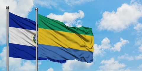 El Salvador and Gabon flag waving in the wind against white cloudy blue sky together. Diplomacy concept, international relations.