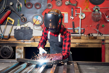 Industrial work, welder works with metal, sparks and fire on background of workplace