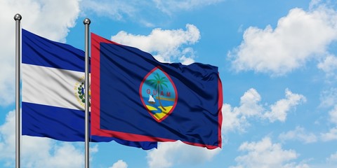 El Salvador and Guam flag waving in the wind against white cloudy blue sky together. Diplomacy concept, international relations.
