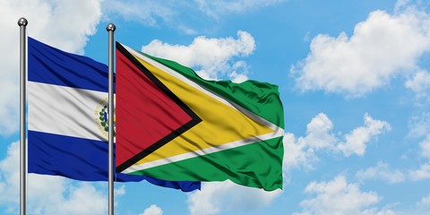 El Salvador and Guyana flag waving in the wind against white cloudy blue sky together. Diplomacy concept, international relations.