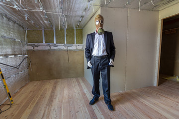 Fototapeta premium Strange man in businessman suit and gas protection mask inside a room under renovation works.