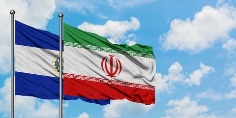 El Salvador and Iran flag waving in the wind against white cloudy blue sky together. Diplomacy concept, international relations.