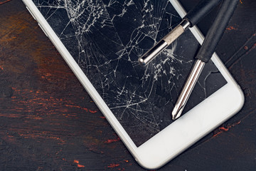 Smartphone repair concept. Damaged display of smartphone and tools