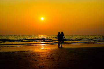 Siluate lovers and beach before sunset