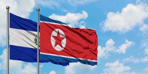 El Salvador and North Korea flag waving in the wind against white cloudy blue sky together. Diplomacy concept, international relations.