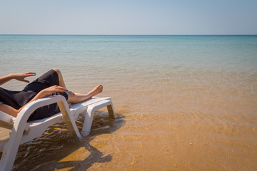 Fototapeta na wymiar Vacation on tropical beach Woman's legs on the beach bed with clear ocean water
