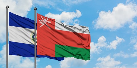 El Salvador and Oman flag waving in the wind against white cloudy blue sky together. Diplomacy concept, international relations.