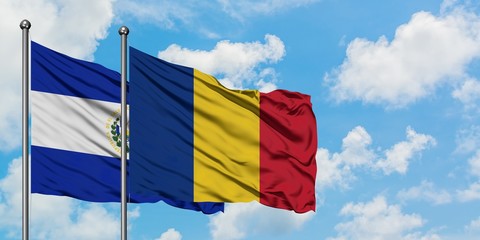 El Salvador and Romania flag waving in the wind against white cloudy blue sky together. Diplomacy...