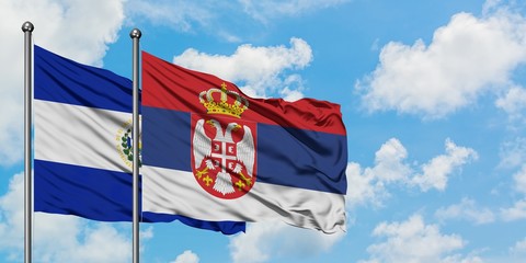 El Salvador and Serbia flag waving in the wind against white cloudy blue sky together. Diplomacy concept, international relations.