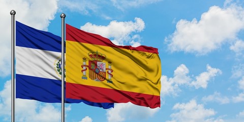 El Salvador and Spain flag waving in the wind against white cloudy blue sky together. Diplomacy concept, international relations.