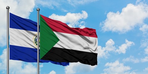 El Salvador and Sudan flag waving in the wind against white cloudy blue sky together. Diplomacy concept, international relations.