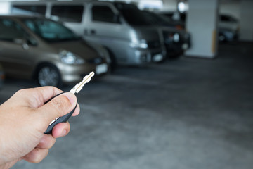 Hand holding car key remote at car park