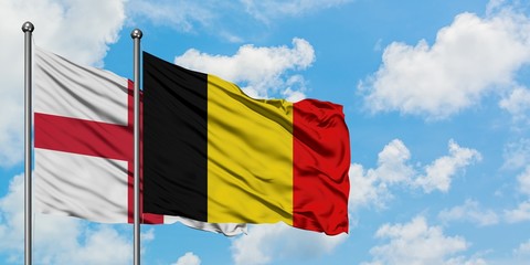 England and Belgium flag waving in the wind against white cloudy blue sky together. Diplomacy concept, international relations.