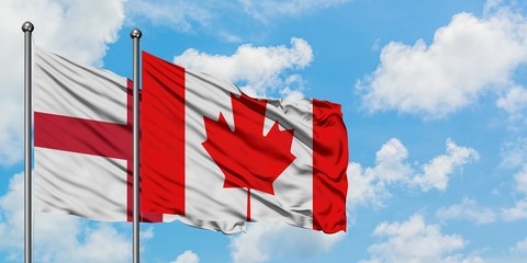 England and Canada flag waving in the wind against white cloudy blue sky together. Diplomacy concept, international relations.