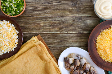 Ingredients for making a snack puff cake of eggs, cheese, herbs, canned fish, mayonnaise on a wooden table.  Copy space. The top view