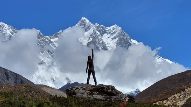 Active hiker hiking, enjoying the view at mount Everest landscape and rise here hand up, static handhed  zoom out shot  