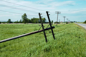 fallen pole standing along the road with wires lying on the ground