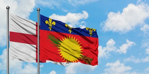 England and Guadeloupe flag waving in the wind against white cloudy blue sky together. Diplomacy concept, international relations.