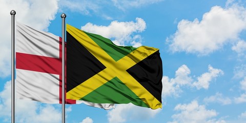 England and Jamaica flag waving in the wind against white cloudy blue sky together. Diplomacy concept, international relations.