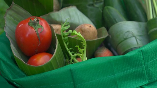 Eco-friendly product packaging concept. Vegetables wrapped in a banana leaf, as an alternative to a plastic bag. Zero waste concept. Alternative packaging