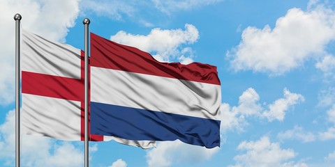 England and Netherlands flag waving in the wind against white cloudy blue sky together. Diplomacy concept, international relations.