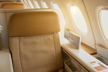 Business or first class seat of the airline have brown color near windows with sun light.They feel luxury , comfort and private when travel or work.Jet airplane and commercial are use for transport.