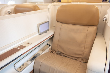 Business or first class seat of the airline have brown color near windows with sun light.They feel luxury , comfort and private when travel or work.Jet airplane and commercial are use for transport.