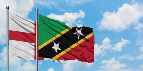 England and Saint Kitts And Nevis flag waving in the wind against white cloudy blue sky together. Diplomacy concept, international relations.