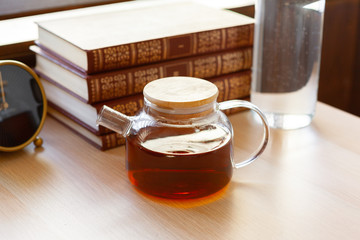 Glass tea pot with black tea on wooden table