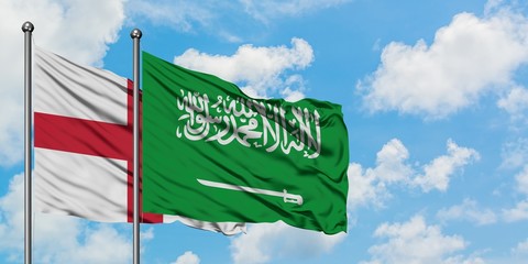 England and Saudi Arabia flag waving in the wind against white cloudy blue sky together. Diplomacy concept, international relations.