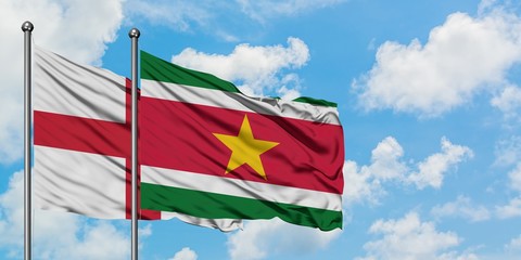 England and Suriname flag waving in the wind against white cloudy blue sky together. Diplomacy concept, international relations.