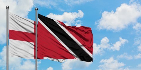 England and Trinidad And Tobago flag waving in the wind against white cloudy blue sky together. Diplomacy concept, international relations.