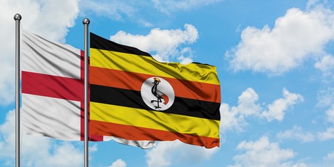 England and Uganda flag waving in the wind against white cloudy blue sky together. Diplomacy concept, international relations.