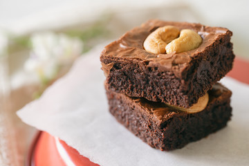 Fresh baked dark chocolate fudge brownies topping with cashew nut stacked on white paper. Delicious taste bitter sweet, chewy and fudgy. Brownie is one type of chocolate cake. Homemade bakery concept.