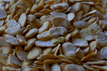 Fava (dry pods) in glass container on white background.