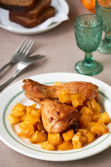 Baked chicken legs with pumpkin on a white plate