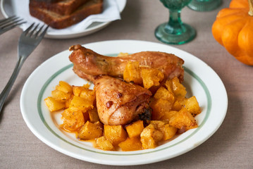 Baked chicken legs with pumpkin on a white plate