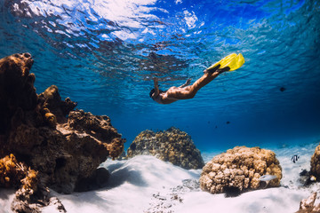 Woman freediver glides over sandy sea with yellow fins in transparent sea. Freediving in Mauritius