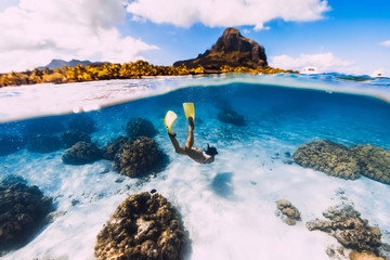 Woman freediver glides over sandy sea with yellow fins in transparent sea. Freediving in Mauritius