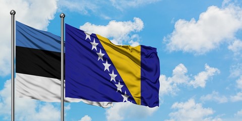 Estonia and Bosnia Herzegovina flag waving in the wind against white cloudy blue sky together....