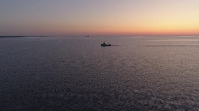 Fishing boat trawling on sea after sunset aerial shot