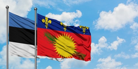 Estonia and Guadeloupe flag waving in the wind against white cloudy blue sky together. Diplomacy concept, international relations.