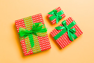 Gift box with green bow for Christmas or New Year day on orange background, top view