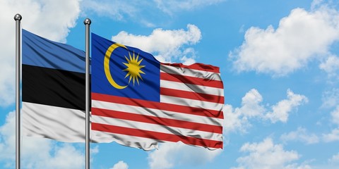 Estonia and Malaysia flag waving in the wind against white cloudy blue sky together. Diplomacy concept, international relations.