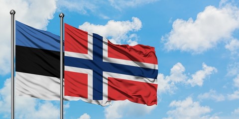 Estonia and Norway flag waving in the wind against white cloudy blue sky together. Diplomacy concept, international relations.