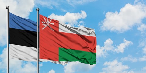 Estonia and Oman flag waving in the wind against white cloudy blue sky together. Diplomacy concept, international relations.
