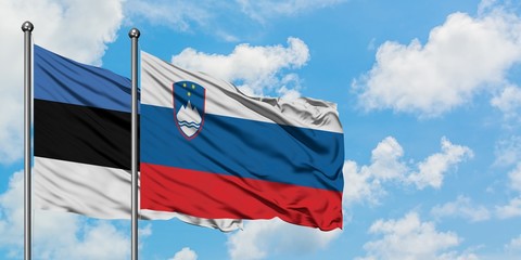 Estonia and Slovenia flag waving in the wind against white cloudy blue sky together. Diplomacy concept, international relations.
