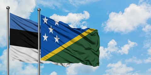 Estonia and Solomon Islands flag waving in the wind against white cloudy blue sky together. Diplomacy concept, international relations.