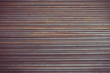 The round steel hollow wire inside, rusted, real colors, dirty, arranged in an orderly manner in the same plane and partial light. Background.Taken at outdoor warehouse in the construction site