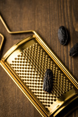 3 Tonkabohnen als Gewürz mit Gold Muskatreibe auf dunkel braun Holz Hintergrund